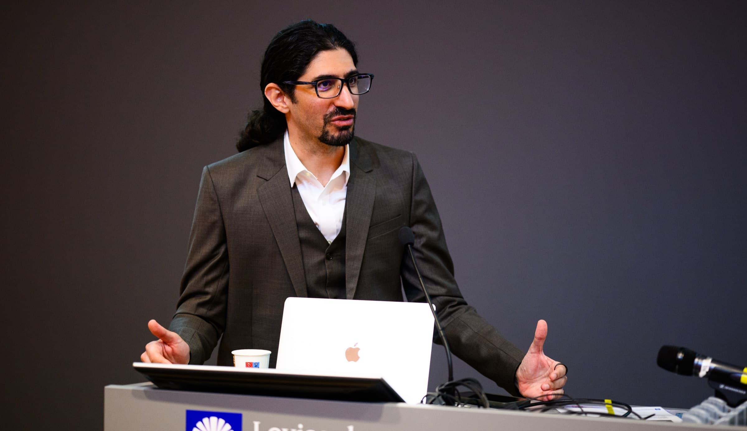 Carlo Mahfouz delivering a keynote, arms open to the room